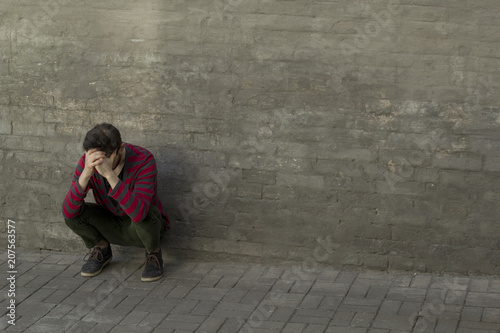 Depressed young man. A sad guy sits and clings to his head. Copy space.