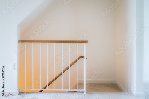 Inside house home interior, townhouse with stairs, steps or staircase leading down to basement level with yellow light lamp glowing, railing