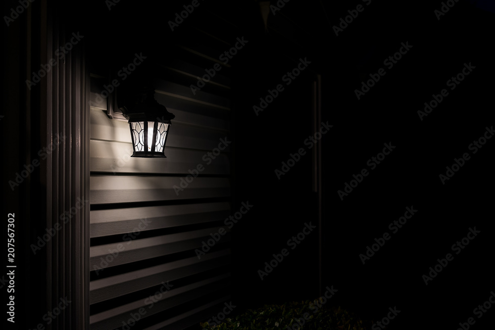 Dark night evening with house exterior lamp lantern, illuminated front door  porch with black background on wall siding Stock Photo | Adobe Stock