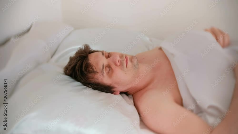 Man is sleeping in bed alone under the blanket. Side view. Man is sleeping in bed alone under the blanket. Side view.