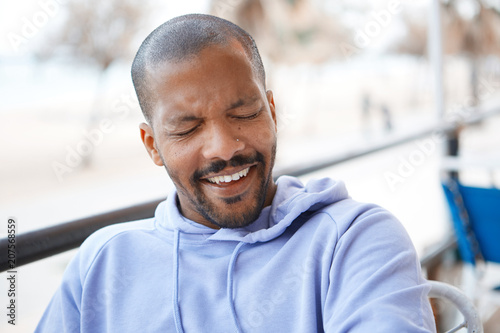 Closeup portrait of happy confident young African-American man hipster in sport hoody smiling.Blurred city on background.