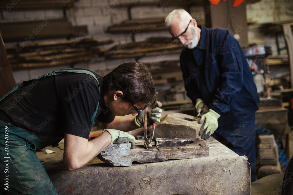 Two master carpenters working together in their woodwork or workshop. Two master carpenters working together in their woodwork or workshop.