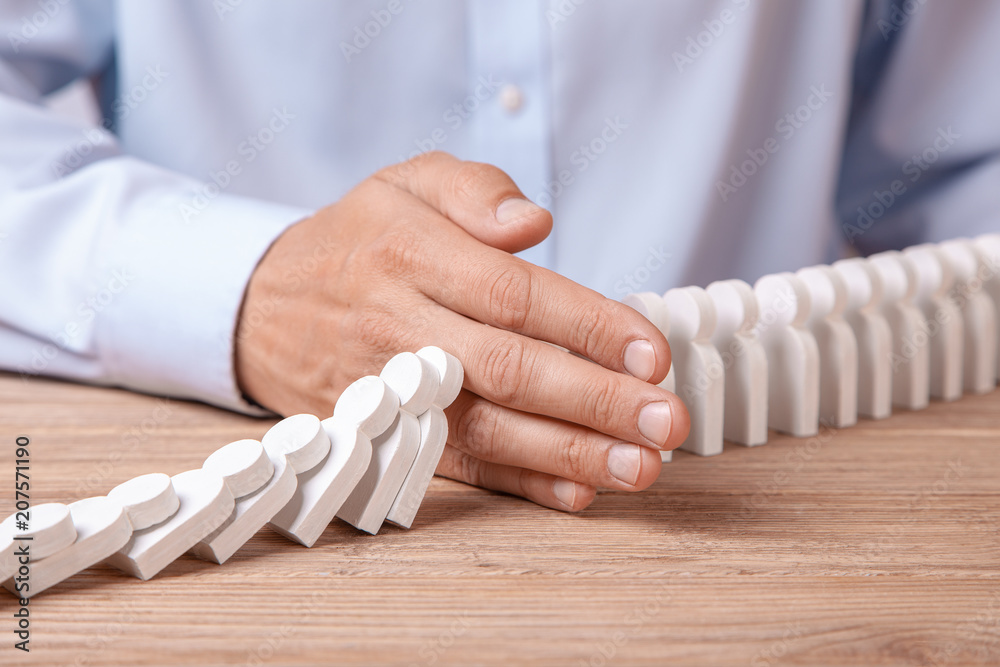 Domino effect of people. Man with his hand covers the fall of little men. The concept of the destruction of the company