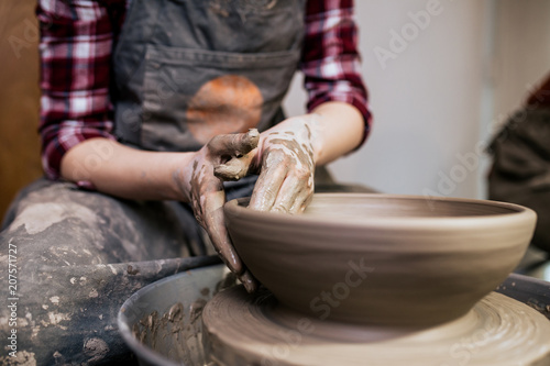 Female potter making clay pottery on a spin wheel.