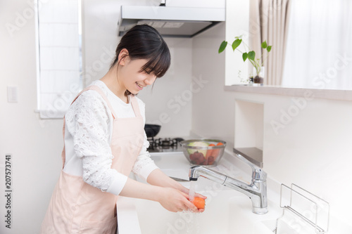 キッチンでニンジンを洗う女の子