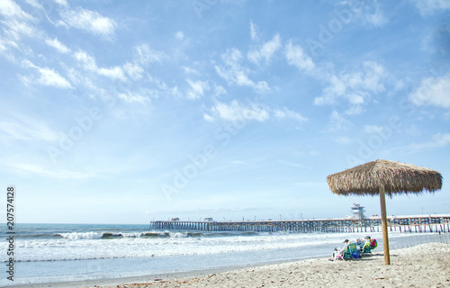 Textured photograph of beach chairs under a palm umbrella at the beach with the pier 