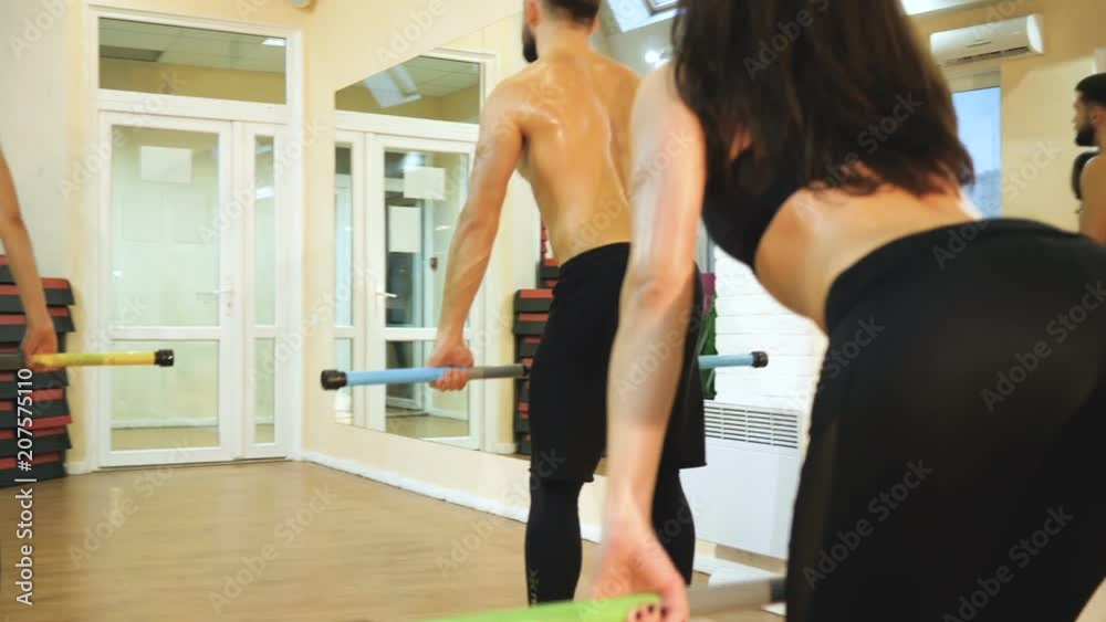A group of athletes are engaged with a gymnastic stick in the gym A group of athletes are engaged with a gymnastic stick in the gym