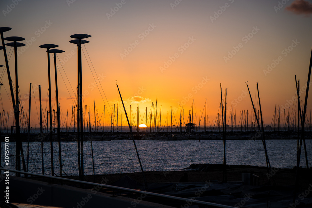 Sunset over water behind boats and yachts at marina