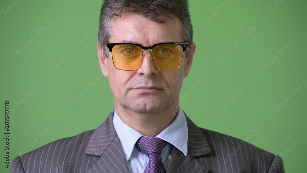 Mature handsome businessman against green background