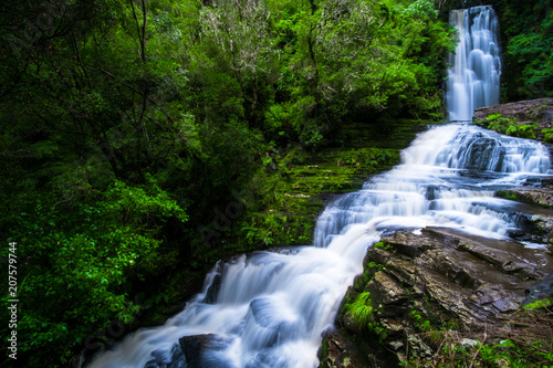 Fototapeta Naklejka Na Ścianę i Meble -  Long Exposure photography. Beautiful waterfall in the rainforest with green nature. Purakaunui Falls, The Catlins, New Zealand.