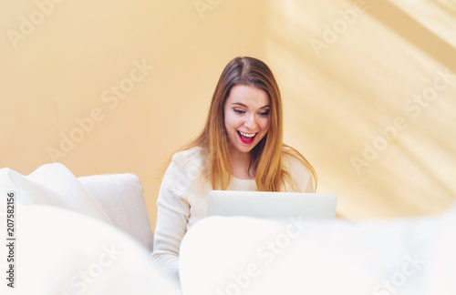 Happy young woman using her laptop computer at home