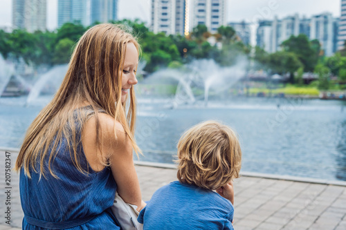 Happy mom with little son enjoying water fountains photo