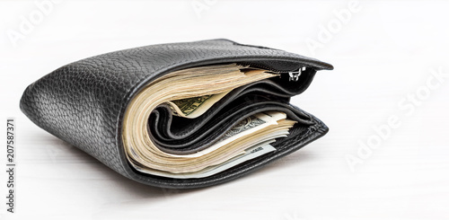 Full wallet with money on white wooden background.