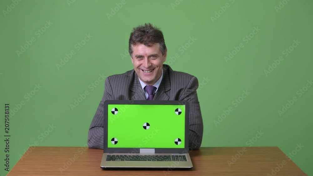Mature handsome businessman against green background Mature handsome businessman against green background