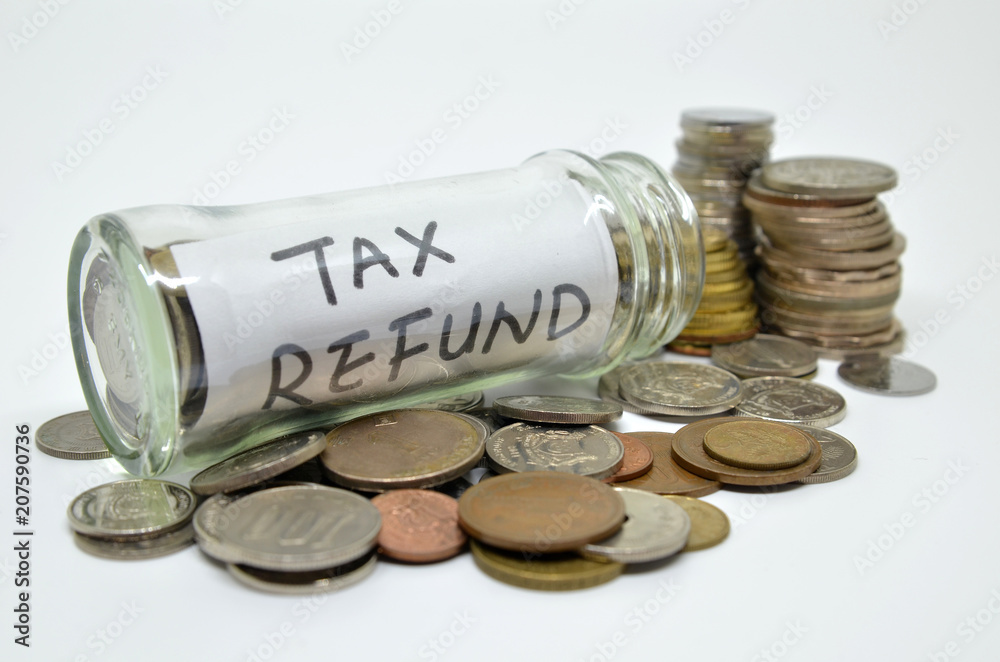 Tax refund lable in a glass jar with coins spilling out Tax refund lable in a glass jar with coins spilling out
