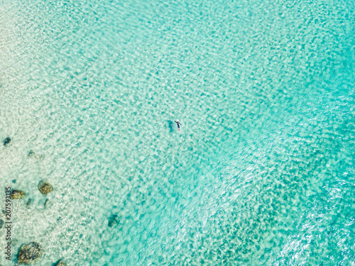 An aerial view of a surfer paddling in blue water on Queensland's Gold Coast in Australia