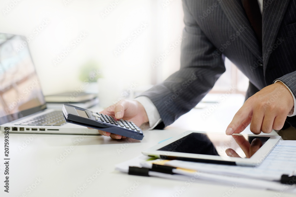 Close up businessman calculate finance data in tablet computer and calculator.