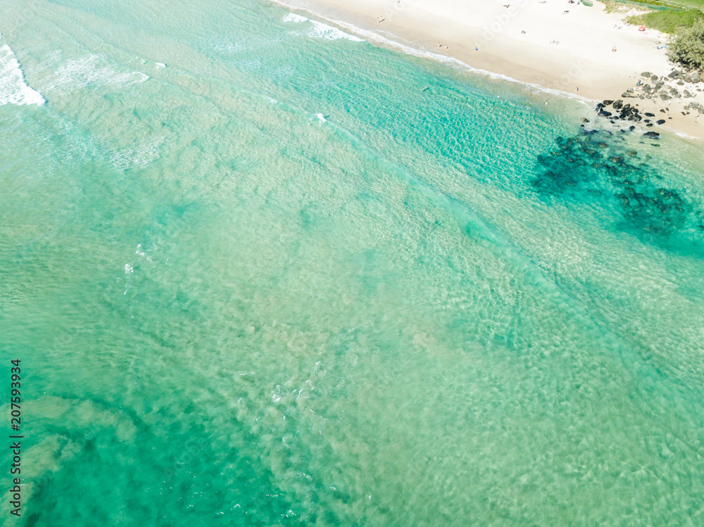 An aerial view of a surfer paddling in blue water on Queensland's Gold Coast in Australia