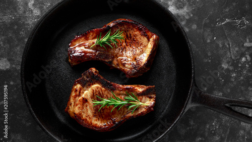 Konstfotografi Cooked Pork Loin chops in rustic skillet, pan with rosemary