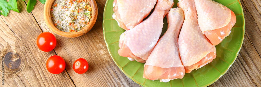 Raw chicken legs on a cutting board on an old wooden table.