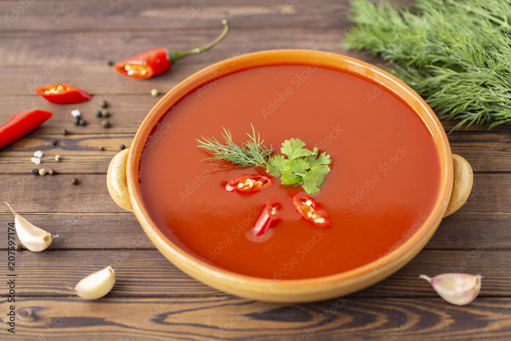 Spicy tomato soup on a wooden table, top view Spicy tomato soup on a wooden table, top view