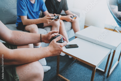 Young friends sitting on a sofa in living room and playing video games. Family relaxing time at home concept.
