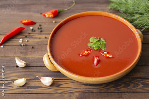 Spicy tomato soup on a wooden table, top view