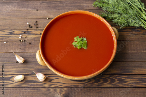 Spicy tomato soup on a wooden table, top view