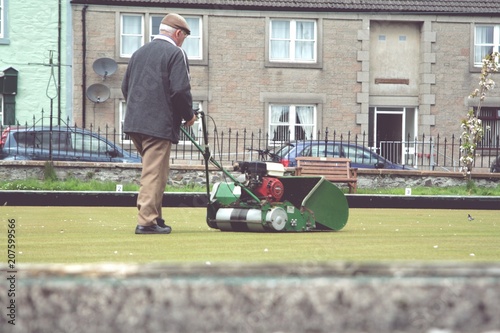Older man mowing the bowling green