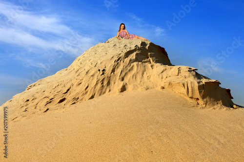 Piękna rudowłosa dziewczyna leży na piaszczystej wydmy.