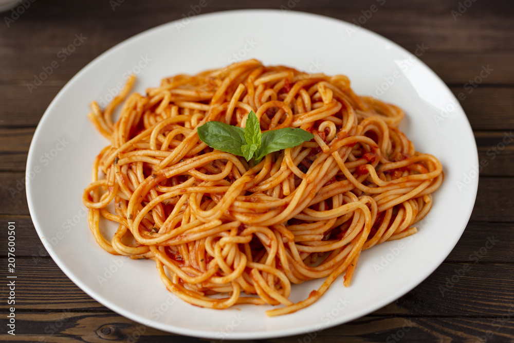 Spaghetti with tomato sauce in the dish on the wooden table
