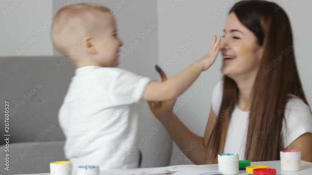 attractive young mom with cute blondy son painting by palms. Smiling, laughing attractive young mom with cute blondy son painting by palms. Smiling, laughing