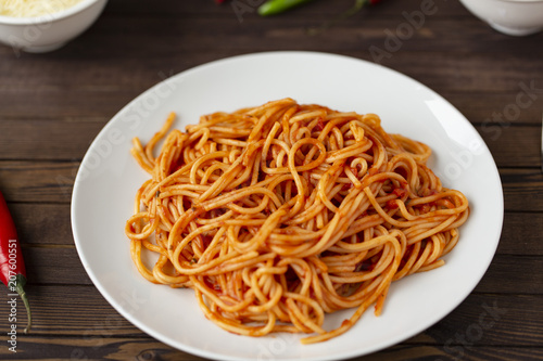 Spaghetti with tomato sauce in the dish on the wooden table