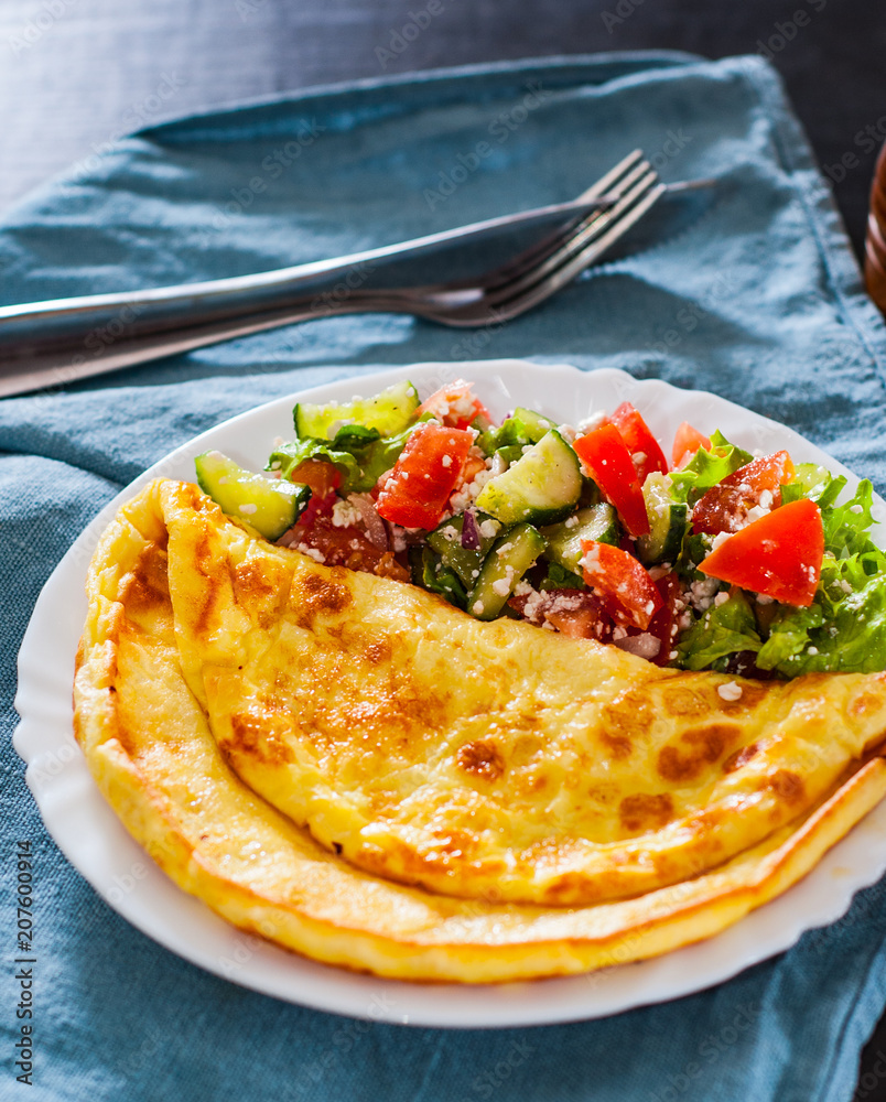 Omelet with vegetable salad in white plate on table Omelet with vegetable salad in white plate on table