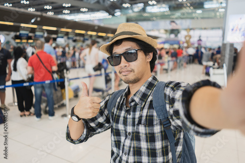Asian man tourist taking a selfie with smart phone camera in airport.