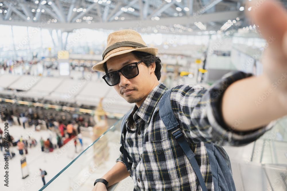Asian man tourist taking a selfie with smart phone camera in airport. Asian man tourist taking a selfie with smart phone camera in airport.