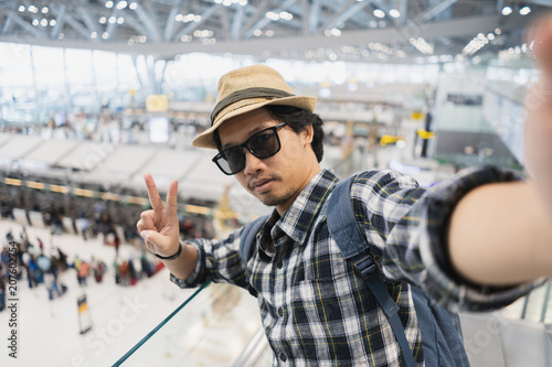 Asian man tourist taking a selfie with smart phone camera in airport.