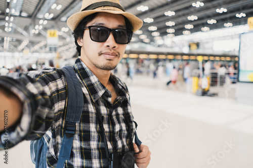 Asian man tourist taking a selfie with smart phone camera in airport.