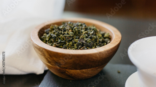 Loose oolong green tea leaves in wood bowl