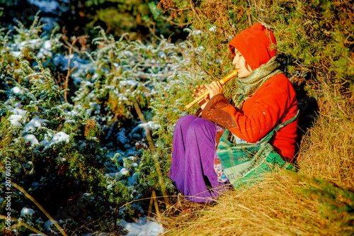 beautiful girl in a historical costume playing her flute in forest.