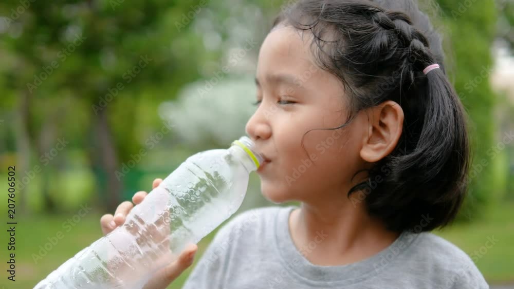 Cute Asian little girl drinking water with happiness at nature park Cute Asian little girl drinking water with happiness at nature park