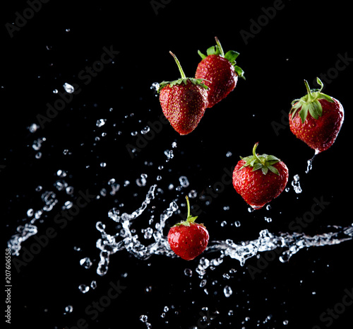 fresh strawberries fall in a spray of water  bright red berries