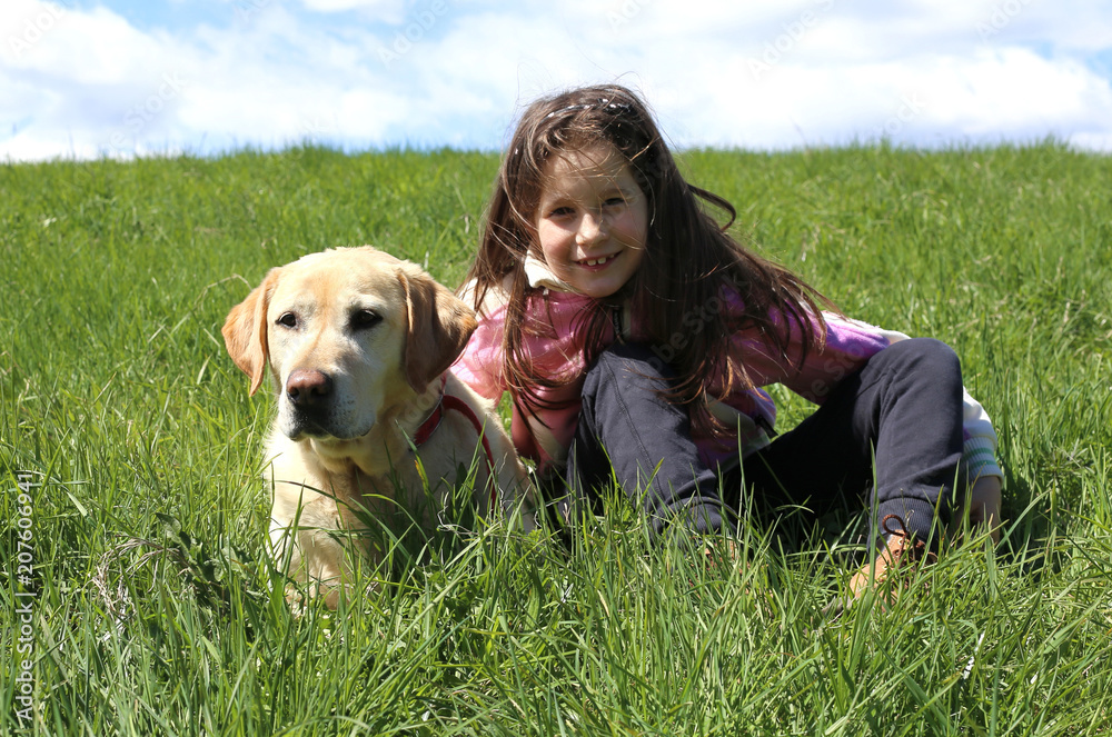 little girl and dog lying on green meadow in the mountains little girl and dog lying on green meadow in the mountains
