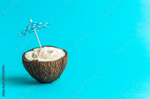 Coconut with paper parasol isolated on blue background.