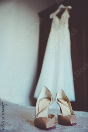 Wedding dress and wedding shoes on the bed.