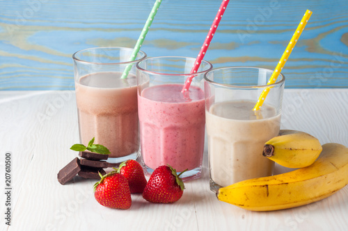 Glasses of milkshakes with chocolate, strawberry, banana flavor, with ice cream on wooden blue and white background. Sweet drinks for summer concept. Shakes and smoothies. Milk shake and cocktail. photo