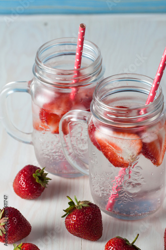 Glasses of strawberry summer water. Cold fruit drinks on white and blue wooden background. Refreshment drinks concept.