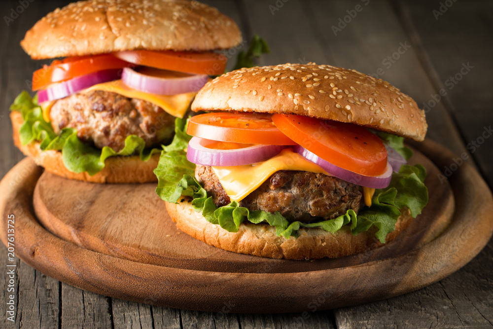 Close-up photo of home made hamburger with beer made of beef, onion, tomato, lettuce, cheese and spices. Fresh burger closeup on wooden rustic table with potato fries and chips. Close-up photo of home made hamburger with beer made of beef, onion, tomato, lettuce, cheese and spices. Fresh burger closeup on wooden rustic table with potato fries and chips.