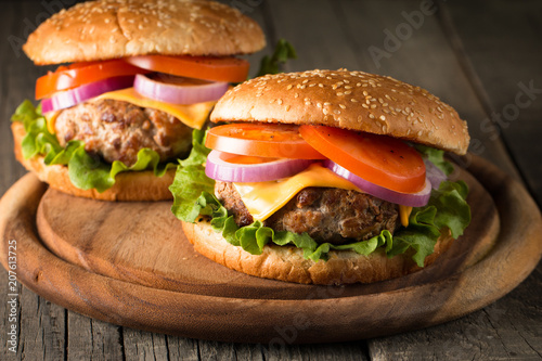 Close-up photo of home made hamburger with beer made of beef, onion, tomato, lettuce, cheese and spices. Fresh burger closeup on wooden rustic table with potato fries and chips.
