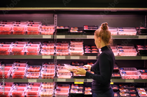 Woman purchasing a packet of meat at the supermarket